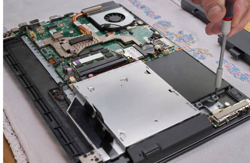 中古パソコンのSSD換装における分解手順。精密ドライバーで内部パーツのネジを外している様子