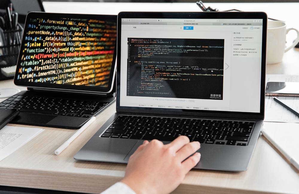 ノートパソコンとタブレットの2つの画面にプログラミングコードが表示され、ユーザーが動作確認を行っている様子