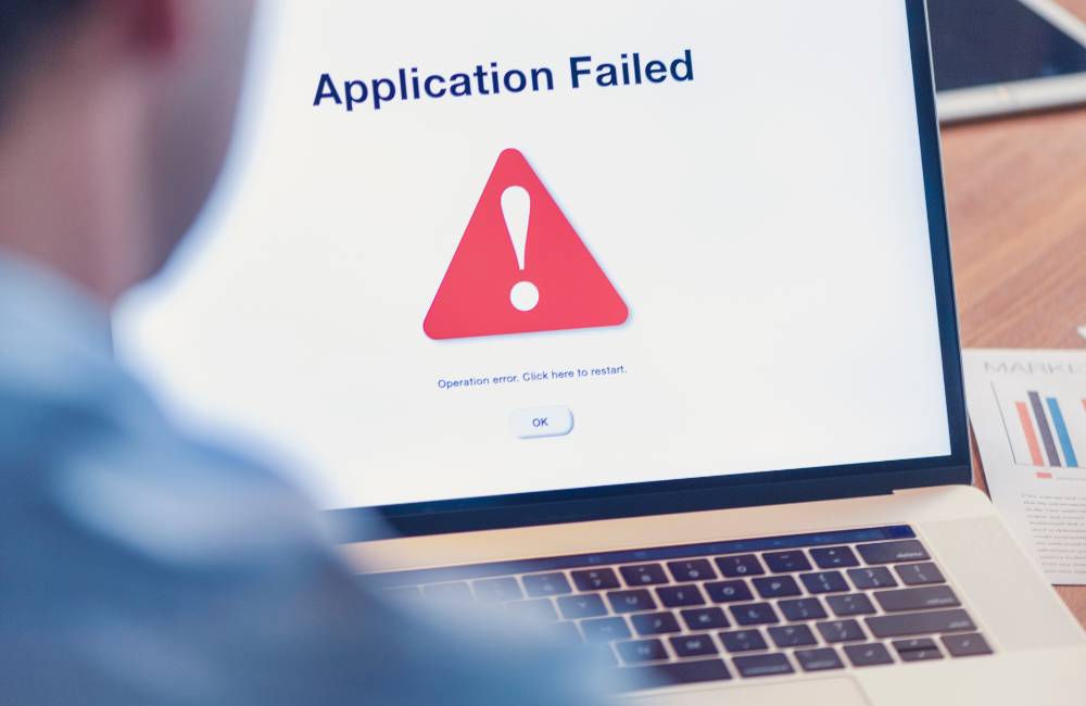 ノートパソコンの画面に大きく表示された「Application Failed」（アプリケーション失敗）の赤い警告マーク。PCトラブルやエラーを回避するための注意喚起。