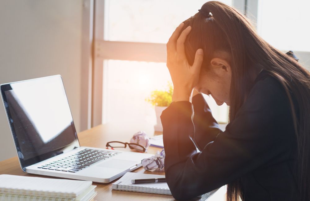 ノートパソコンの異常に困り、頭を抱えている女性