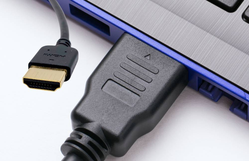HDMIケーブルがノートパソコンに接続されているクローズアップ。変換アダプタを使った安定した接続をイメージするテクニカルな構図。
