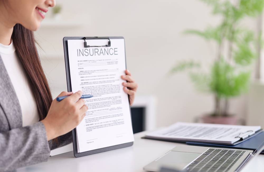 女性が「INSURANCE（保険）」と書かれた契約書を指し示している様子。専門店の「保証」や「安心感」を表現。