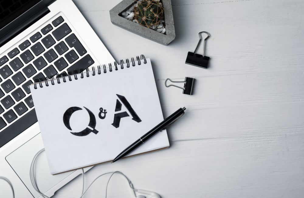 ノートパソコンの横に「Q&A」と書かれたノートが置かれ、中古パソコン購入でよくある質問をイメージした画像