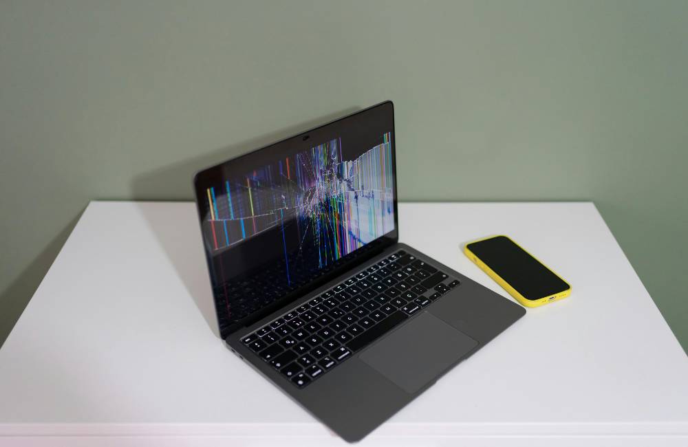 一見すると正常だが、電源を入れると液晶画面が激しく割れて線が入っている故障したノートパソコン。