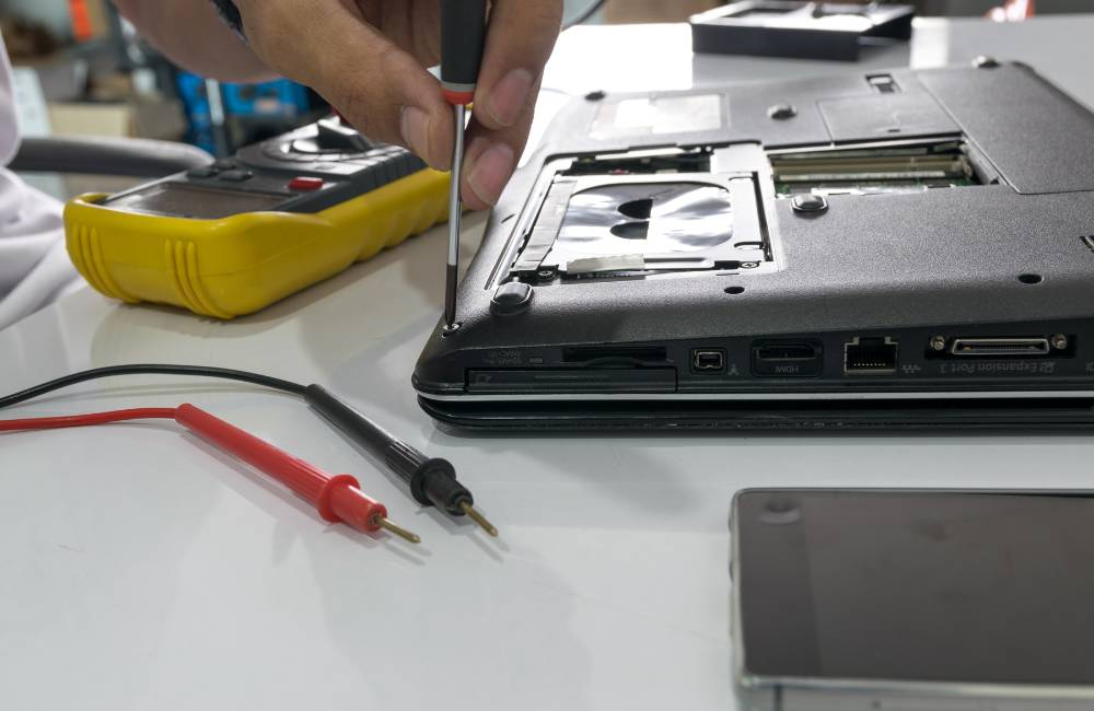 テスターとドライバーを使い、ノートパソコンの通電確認や分解作業を行う様子。ジャンク品活用の仕上げイメージ。