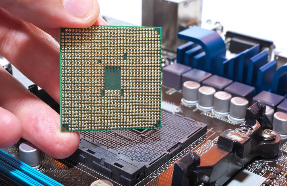 パソコンの基板（マザーボード）にCPUチップを慎重に取り付けようとしている手元のクローズアップ