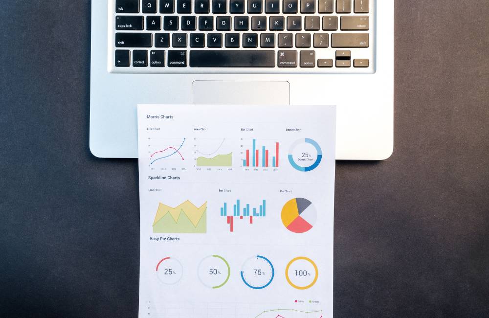 ノートPCの横に置かれたノートと鉛筆、コーヒーカップ。ビジネス書類やデータ分析など、作業効率向上のメリットを連想させる机上の写真。