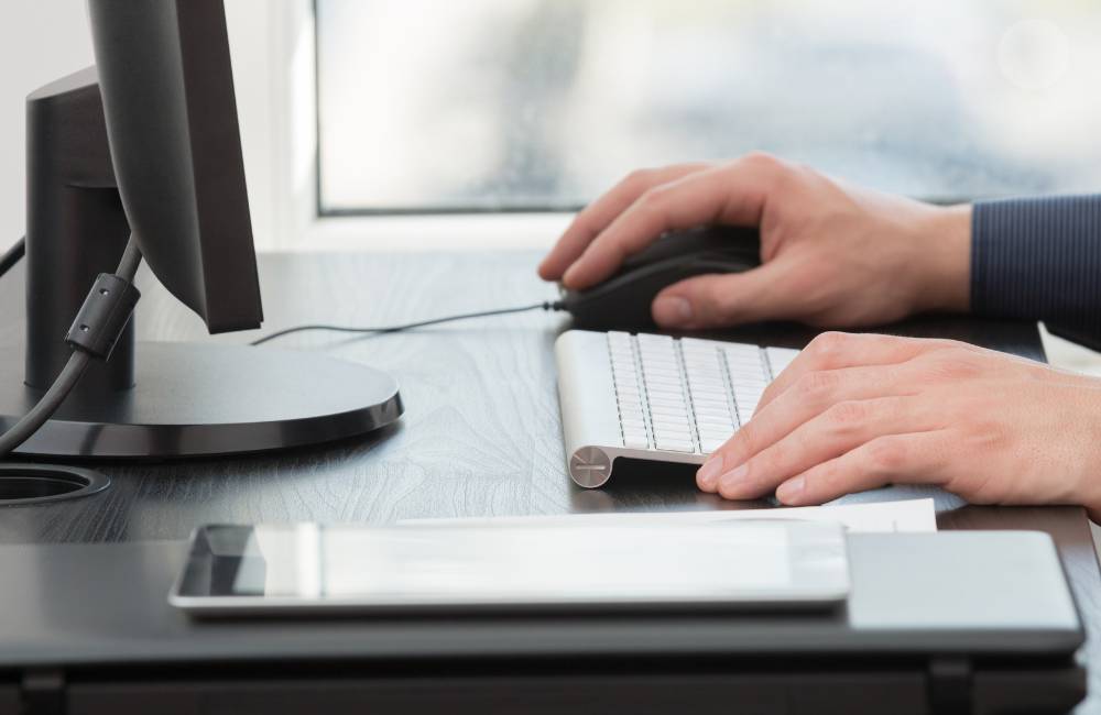 デスクでパソコンを操作する手元の様子。キーボードとマウスを使って作業しているシーン。