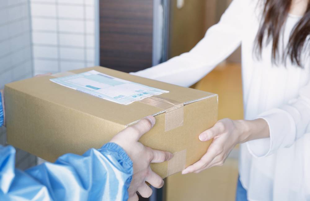 段ボール箱を受け取る人の手元。返品・交換手続きをスムーズに行う様子を表した写真。