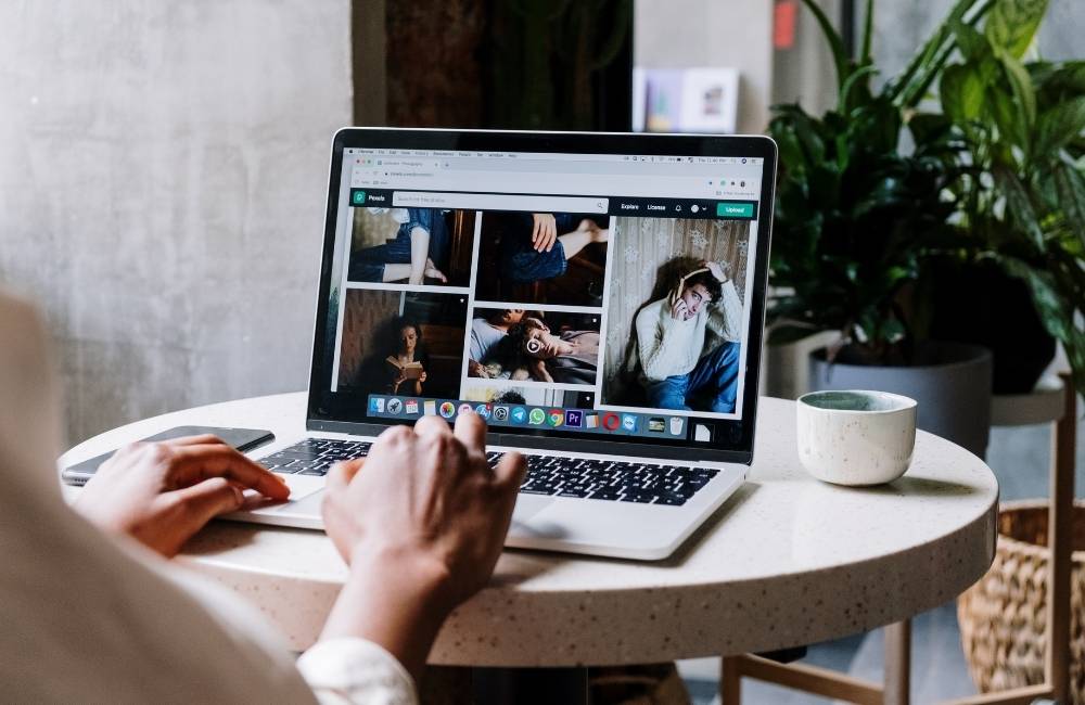 明るいカフェのテーブルでノートパソコンを快適に操作し、Webサイトを閲覧している女性の様子