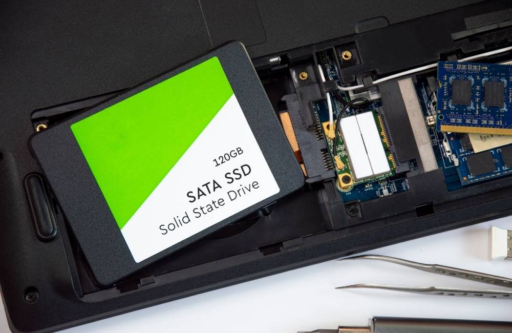 ノートパソコンの内部スロットの横に置かれた、120GBの2.5インチSATA SSDストレージ