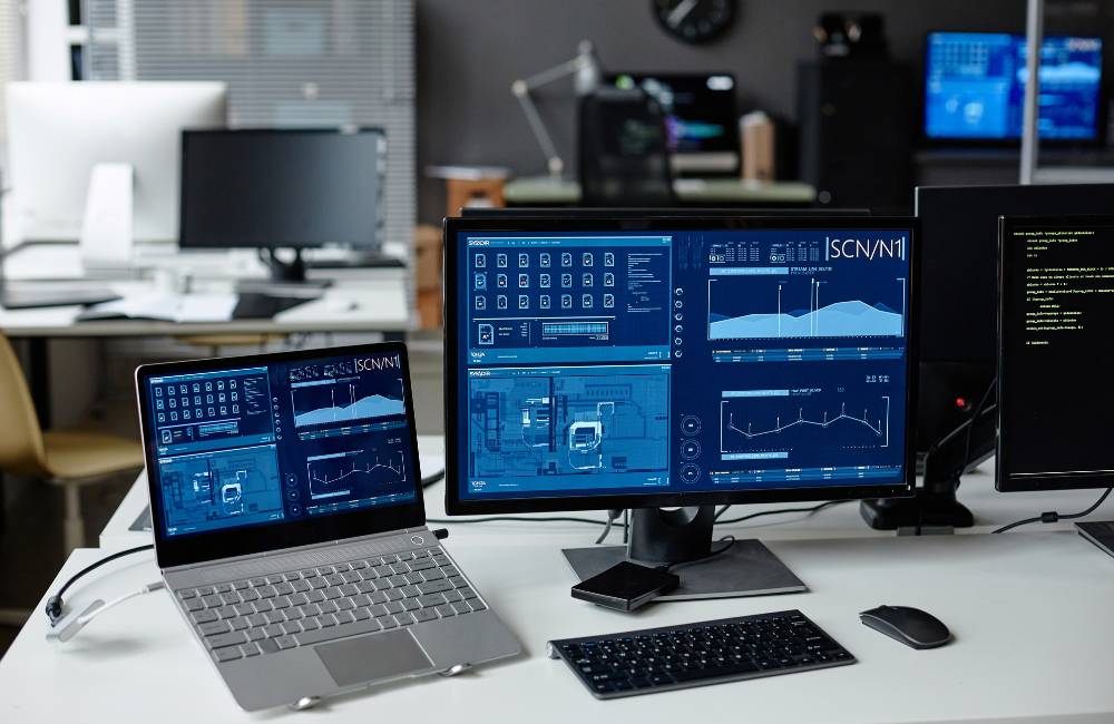 デュアルモニター環境で動画編集を行う女性。片方の画面にはダンス映像、もう片方には空撮映像の編集ソフトが表示されており、高度な作業環境を象徴している。