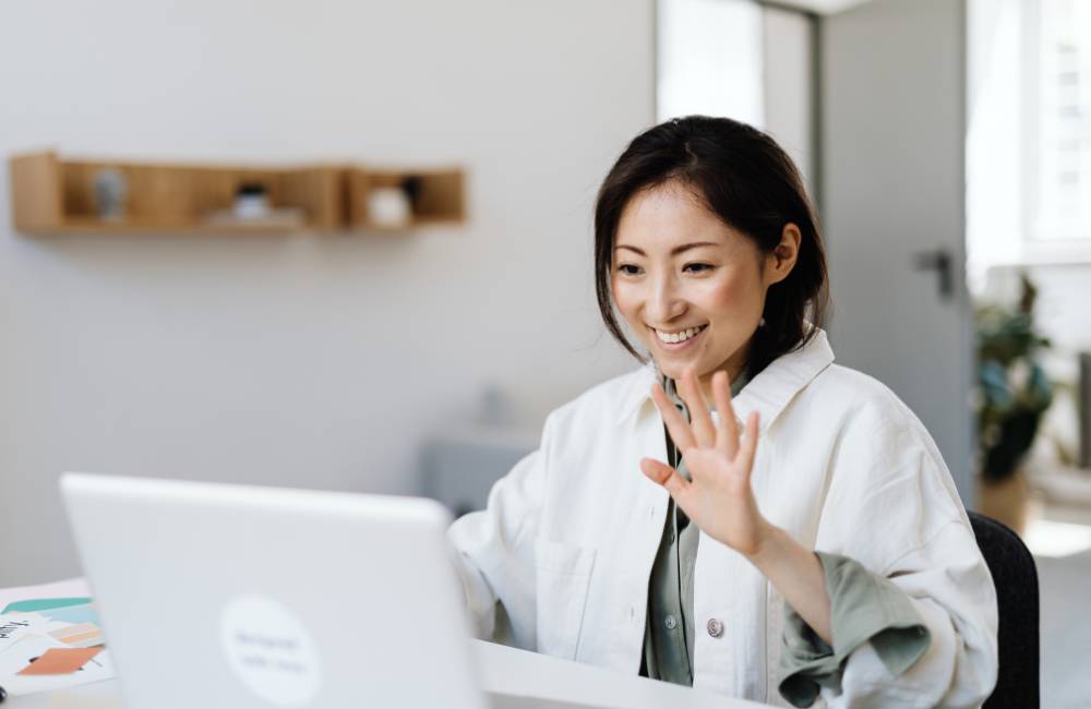 笑顔でノートパソコンを操作する女性。保証付き中古パソコンを安心して利用しているイメージ