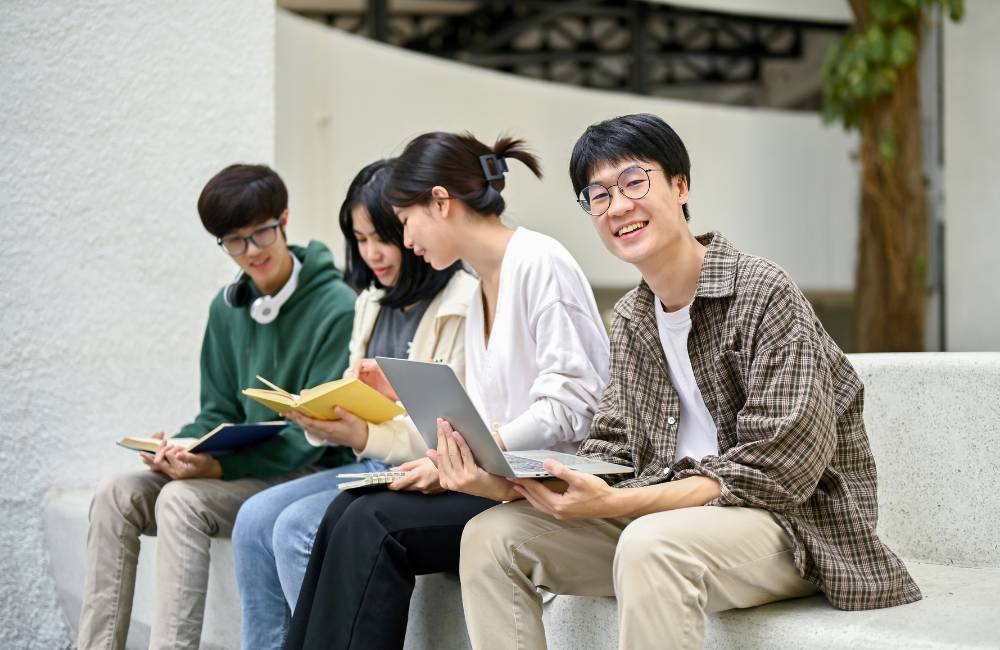 屋外でノートパソコンや教材を使いながら勉強する学生たちの写真