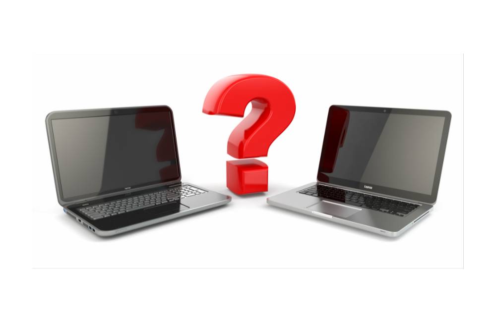 白い背景に置かれた2台のノートパソコンと、その中央に配置された大きな赤いクエスチョンマーク。比較と疑問解消のイメージ。