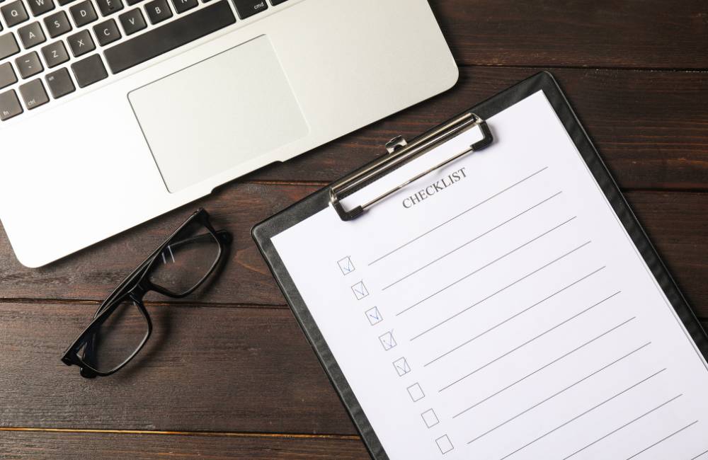 ノートPCとチェックリストが載ったクリップボードと眼鏡