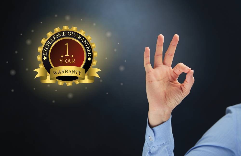 1 YEAR WARRANTYと書かれた金色のエンブレムとOKサインをしているビジネスマンの手