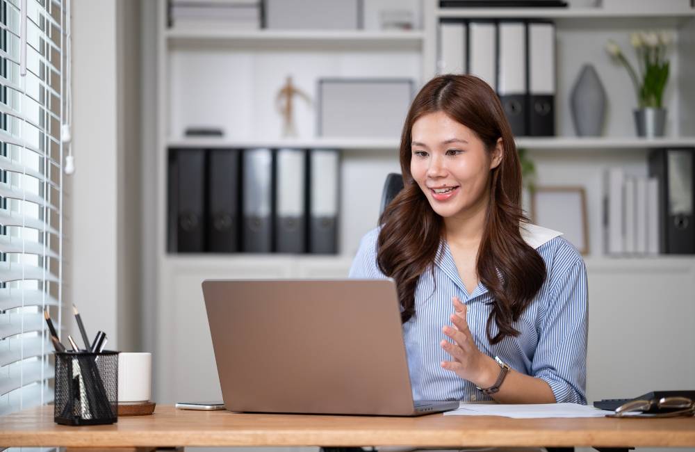 ノートPCでビデオ通話を行い笑顔で話しているビジネスマンの女性