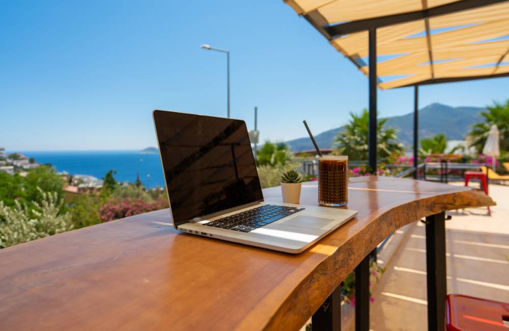 海が見える開放的なテラス席で、太陽の光を感じながら軽快にモバイルPCを操作している自由なワークスタイル。