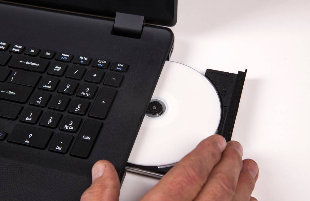 中古PCの側面にある端子やドライブの開閉部を指で差し、状態を細かくチェックしている比較写真。