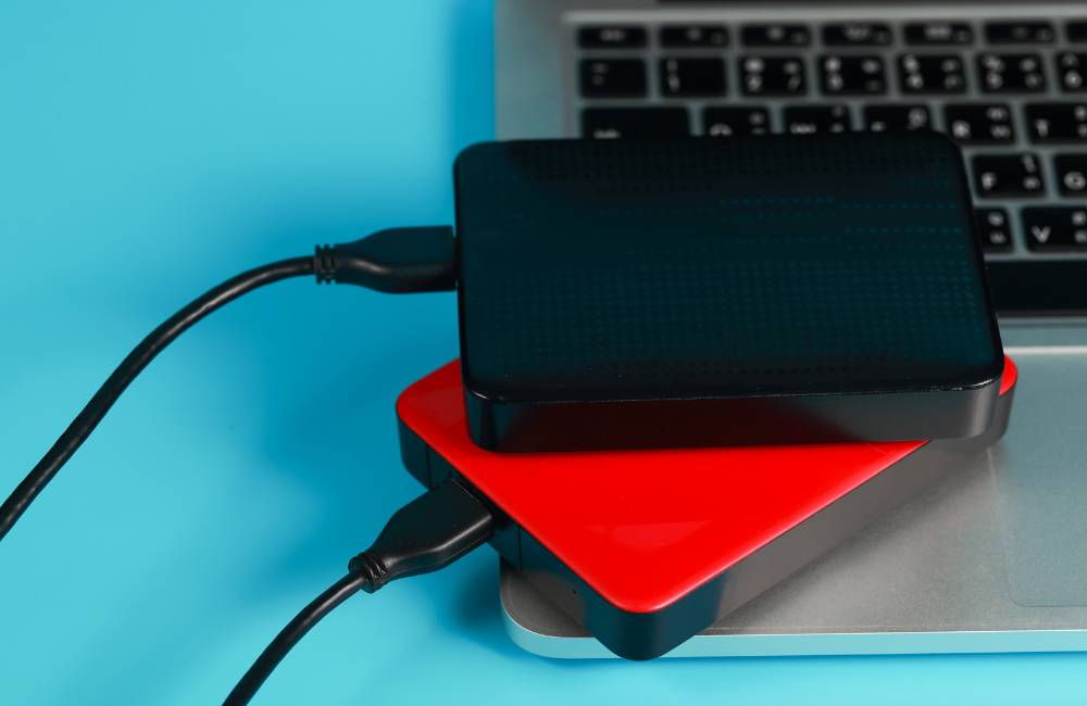 ノートPCのキーボードの上に、黒と赤の2台の外付けハードディスクが並んで置かれている。