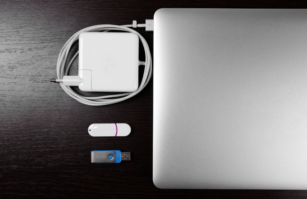 木目調のテーブルに、ノートPC、ACアダプター、そして2本のUSBメモリが整理して置かれている様子。