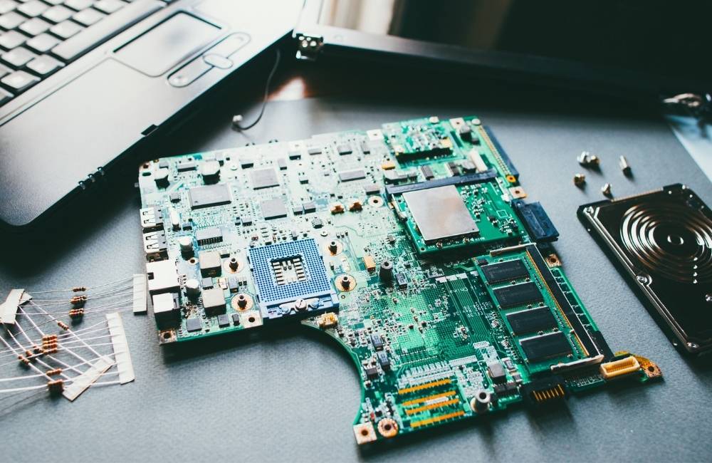 虫眼鏡を使ってパソコンのマザーボード上の細かいチップや型番を詳しく調べている様子