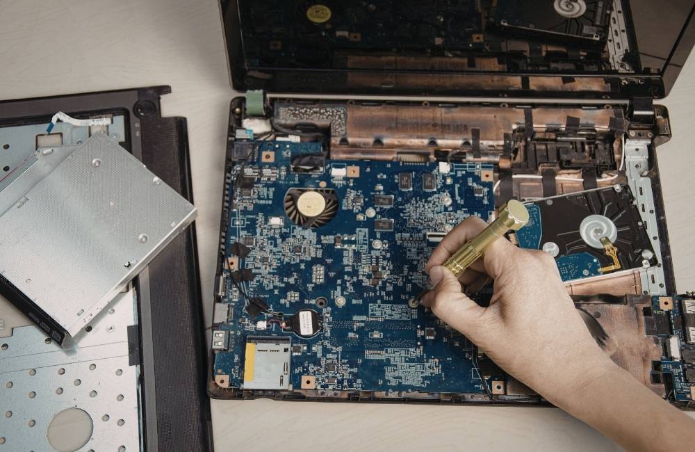 精密ドライバーを使い、電子回路がむき出しになったパソコン内部を慎重にメンテナンスしている様子