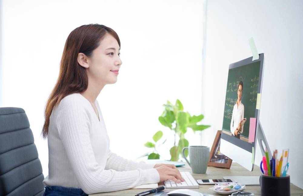 明るいリビングで、アップグレードが終わったノートパソコンが動くのを見て安心した表情を見せる女性