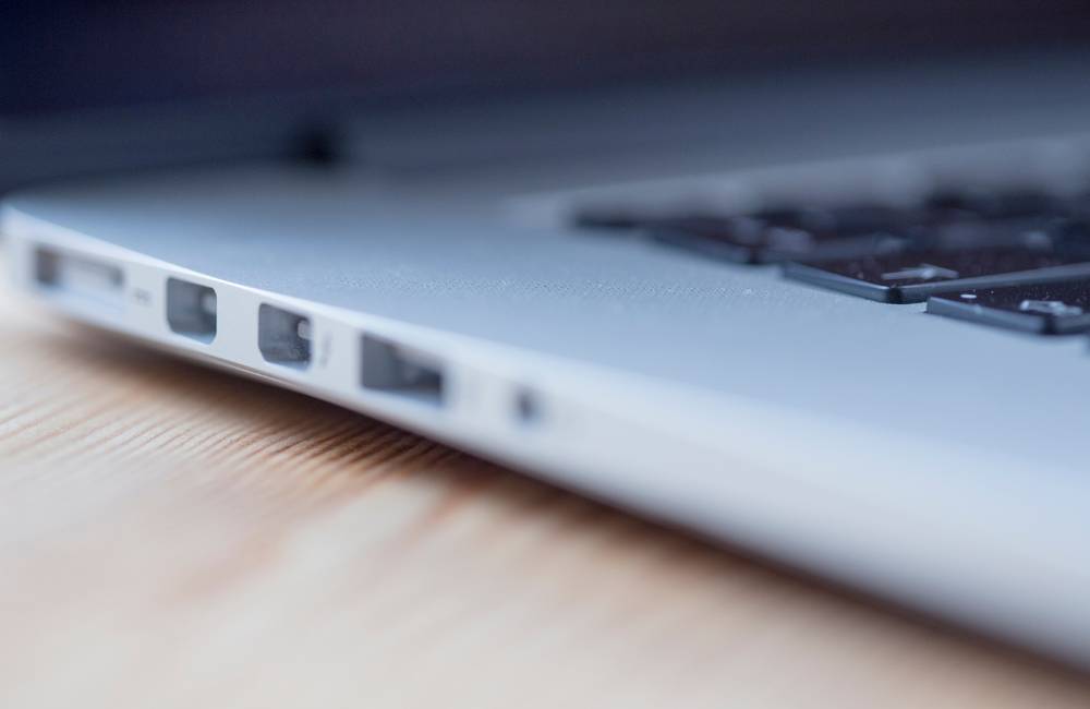 光沢のあるシルバーのノートパソコンの側面をクローズアップ。USBポートやSDカードスロットなど、複数の接続端子が鮮明に写っており、拡張性や接続性を確認する様子を表現。
