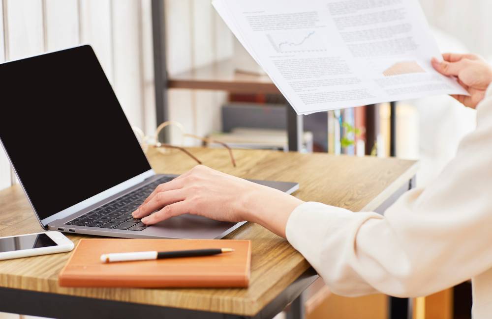 ノートパソコンの横に、グラフや統計データが記載された書類が置かれている様子。3万円台の中古パソコンで狙えるスペック基準とデータの整合性をイメージしています