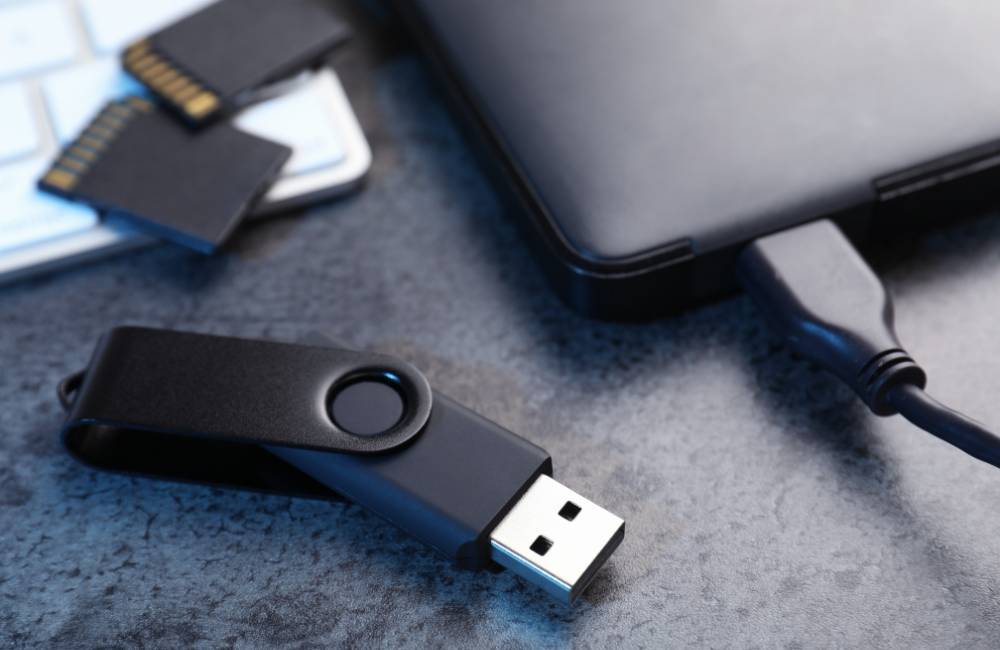 デスクの上に置かれたUSBメモリ、SDカード、外付けハードディスクなどの周辺機器。パソコン購入前に接続端子や保存容量を確認する重要性を伝えています