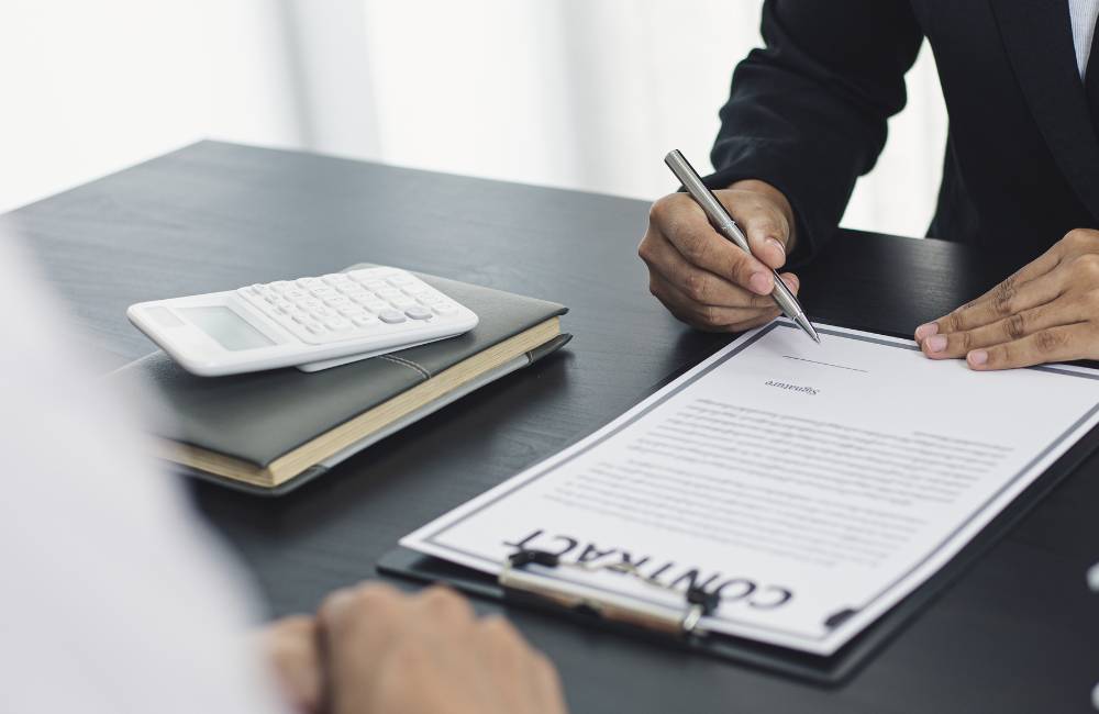 ジネスシーンにおいて、契約書（CONTRACT）にペンで署名をする手元。中古パソコン購入時の保証やサポートなど、安心できる取引をイメージしています