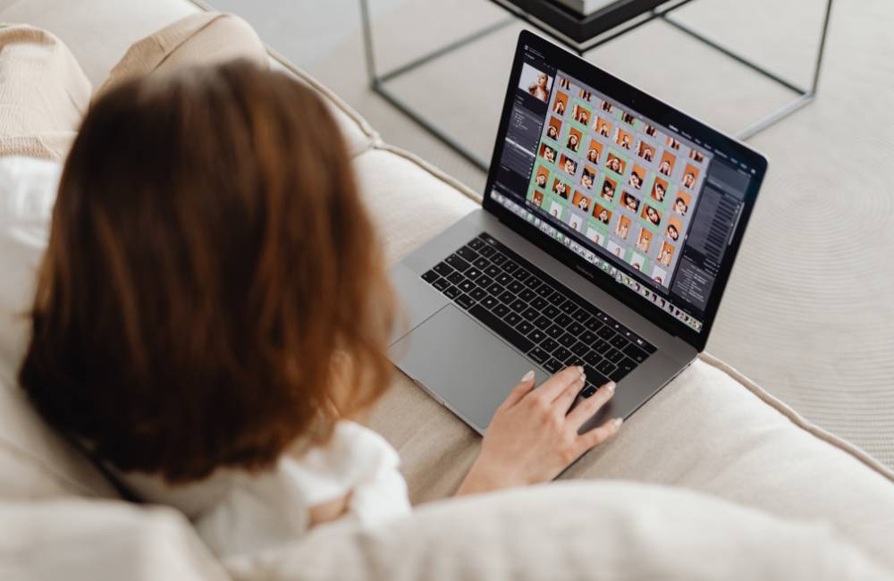 ソファに座ってリラックスしながら、ノートパソコンの画面でたくさんの写真一覧をチェック・編集している手元の様子