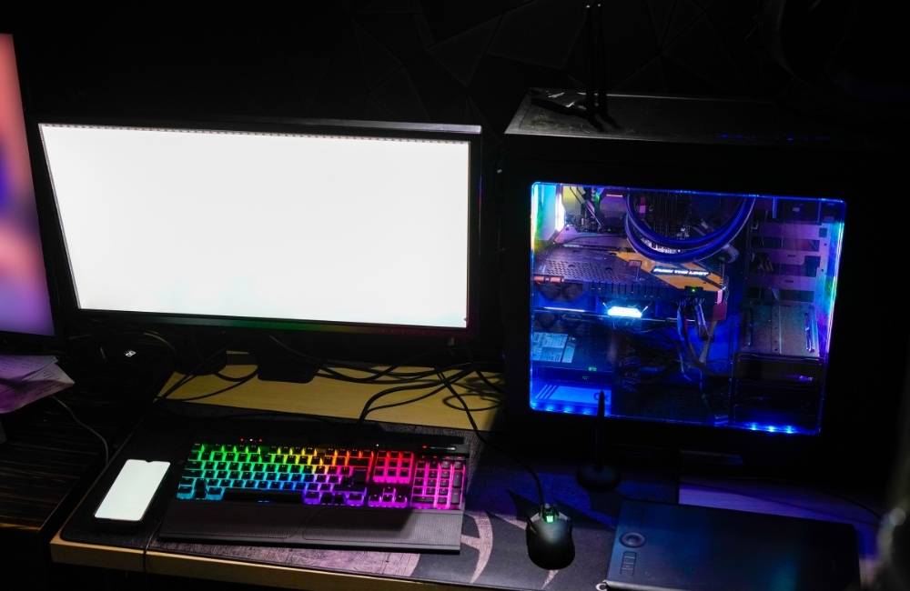 暗い部屋でキーボードがカラフルに光る自作パソコンと、真っ白な画面が表示されたモニター