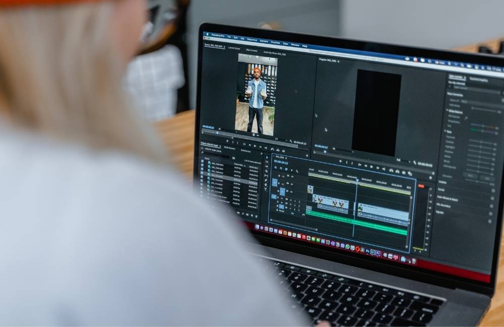 ノートパソコンの画面に映る動画編集ソフトのような複雑なメニューを、真剣に見つめている人物
