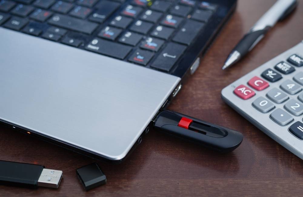 ノートパソコンの側面に、黒いUSBメモリが差し込まれている様子