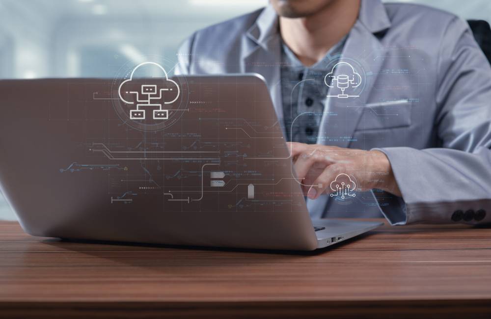 ノートパソコンを操作しながら、クラウド上でデータが同期・管理されている様子を示したイメージ