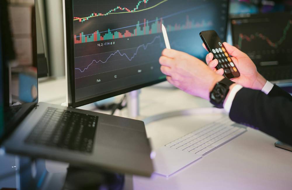 複数のモニターを使い、株価のチャートや複雑なグラフを表示して分析している仕事環境。