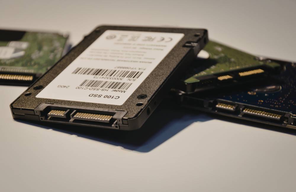 机の上に並べられた、複数の異なるメーカーのSSDとハードディスク。