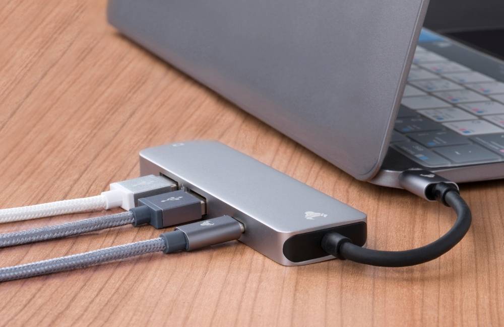 ノートパソコンの横から伸びたアダプターに、何本ものグレーのケーブルが複雑に繋がっている様子。