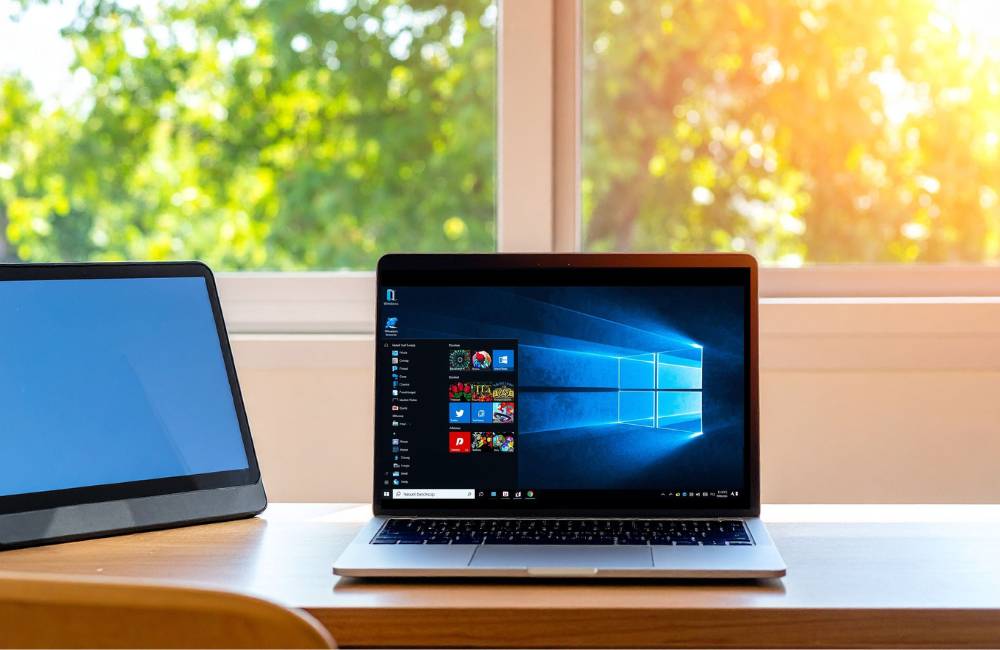 日差しが差し込む部屋で、ノートPCのWindows 11のデスクトップ画面が明るく表示されている。