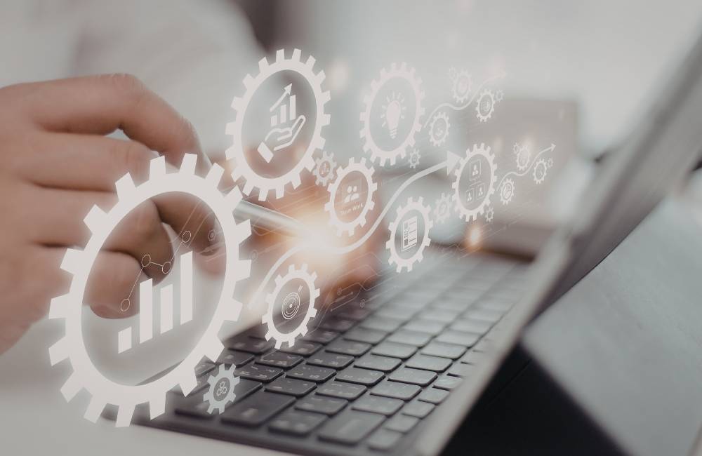 キーボードを打つ手の上に、歯車などのマークが浮かんでいるイメージ画像。