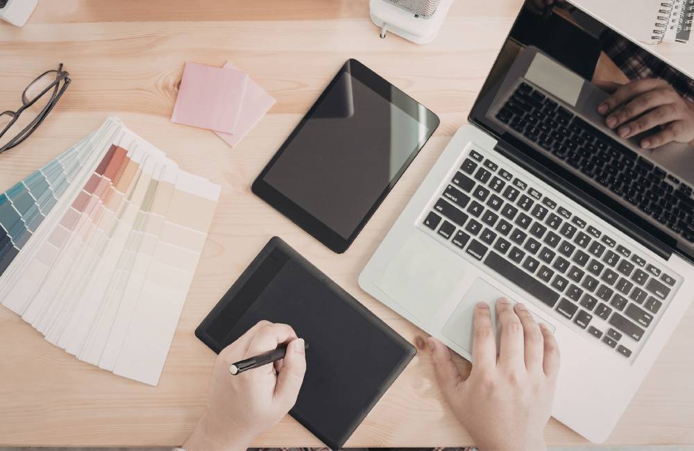 ノートパソコンとペンタブレット、カラーチップを並べて無料アプリを比較・検討している作業風景