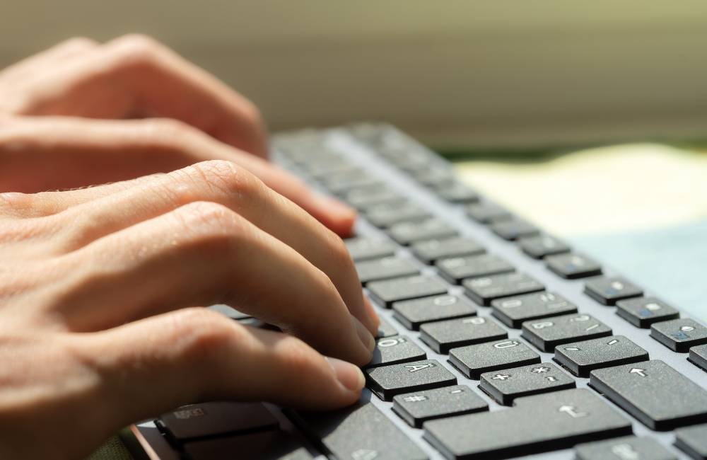 ユーザーがノートパソコンのキーボードに手を置き、実際にタイピングして打ち心地を確認している手元のアップ写真