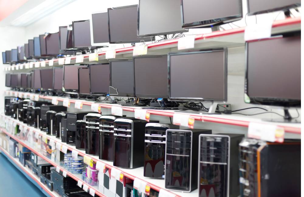店舗の棚に様々なブランドの中古デスクトップPC本体とモニターが複数台陳列されている全景