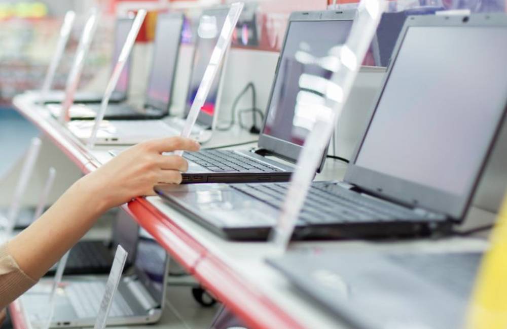 中古パソコン専門店の店頭で複数のノートパソコンを比較しながら選んでいる様子