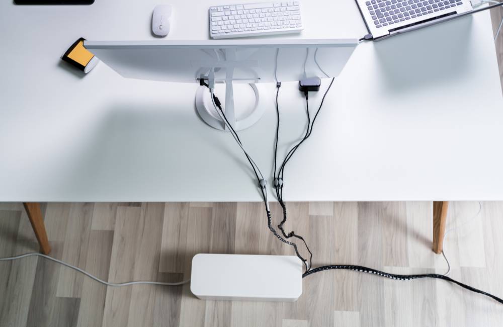 机の上のケーブル類を整理ボックスやホルダーを使って、折れ曲がりや絡まりがないようにスッキリと整理した様子