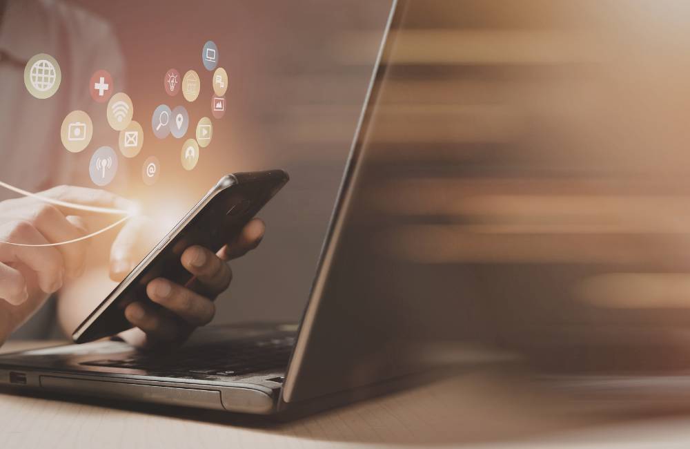 スマートフォンを操作し、様々なアイコンが飛び出している様子(最新のお得な情報をチェックするイメージ)