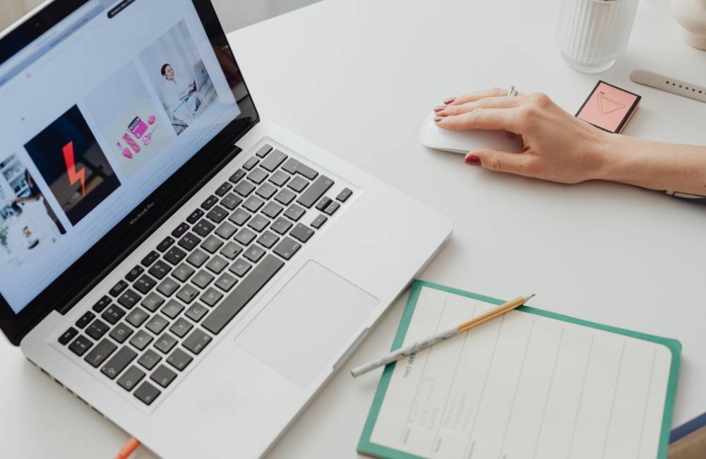 白いデスクでノートパソコンを操作し、メモを取る準備が整った整然としたワークスペース